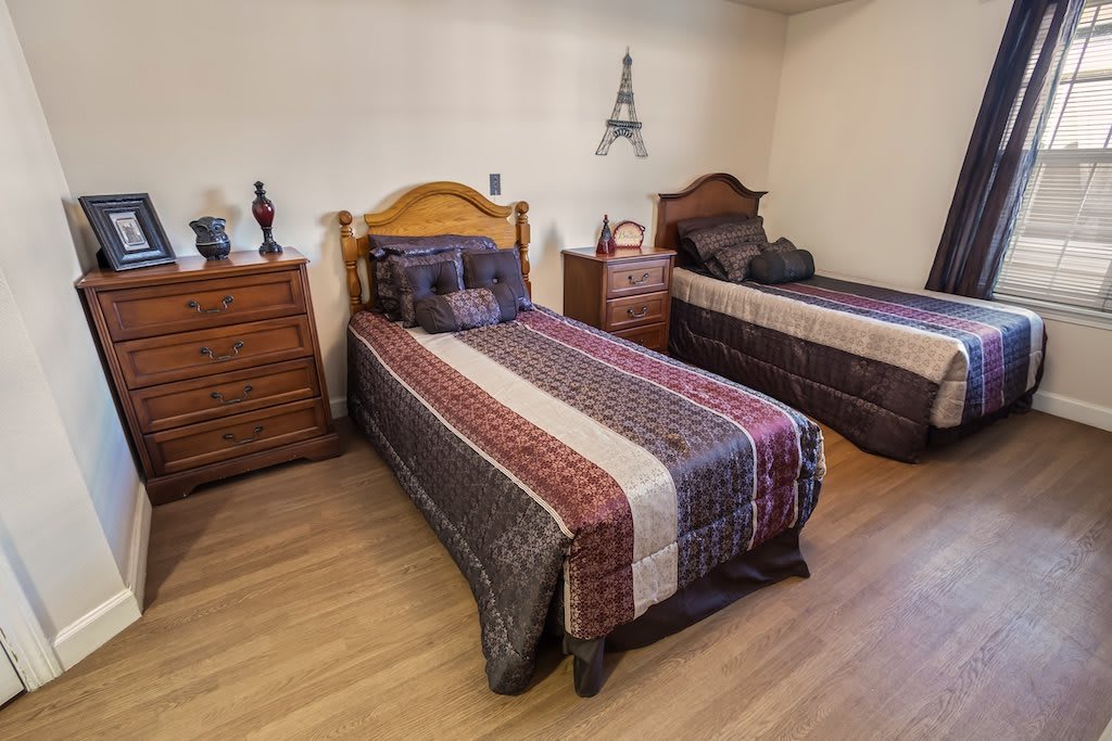 A cozy bedroom with twin beds, featuring traditional wooden furniture and Eiffel Tower wall decor.
