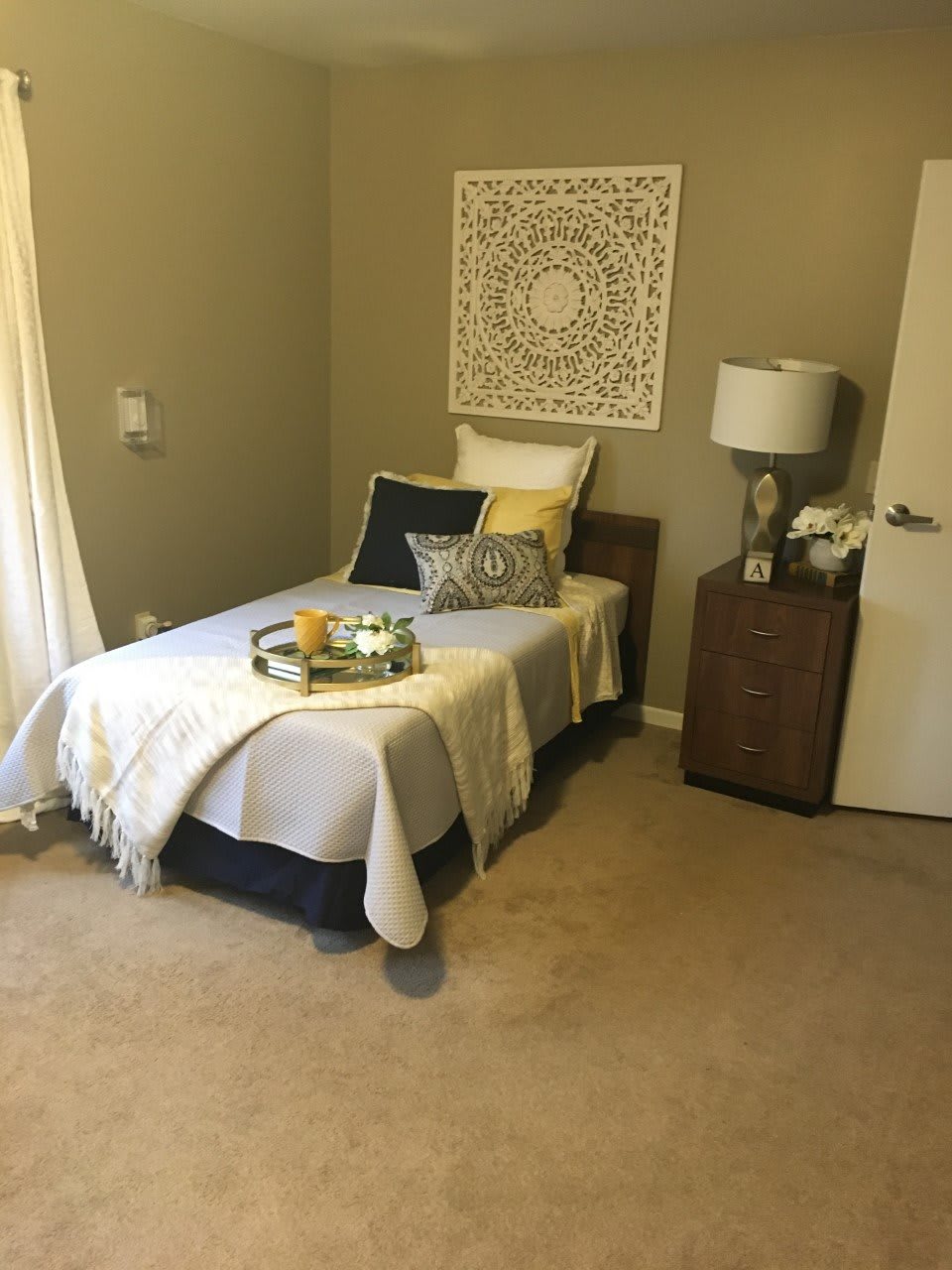 A cozy modern bedroom with a single bed, decorative pillows, and elegant wall art.