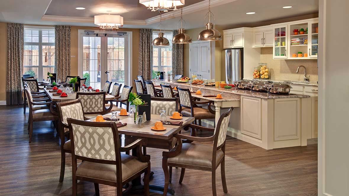 A modern dining room with elegant furnishings and a connected kitchen area.