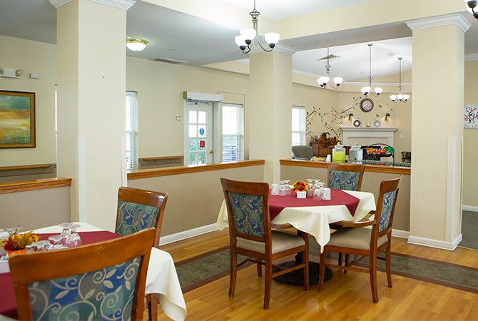 A cozy dining area featuring neatly set tables and chairs, with elegant lighting and a warm ambiance.