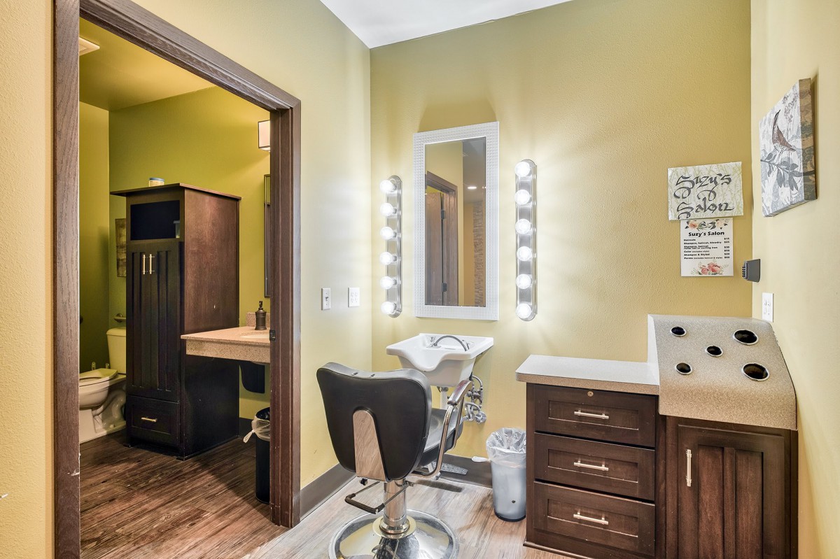 A stylish salon interior with a well-lit mirror and a comfortable chair.