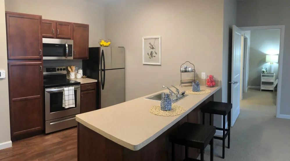 A modern apartment kitchen with a clean countertop and bar stools.