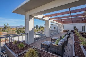 A spacious outdoor patio with seating under a modern pergola, overlooking a scenic landscape.