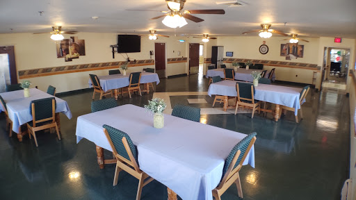 A spacious dining area featuring neatly arranged tables with blue tablecloths.