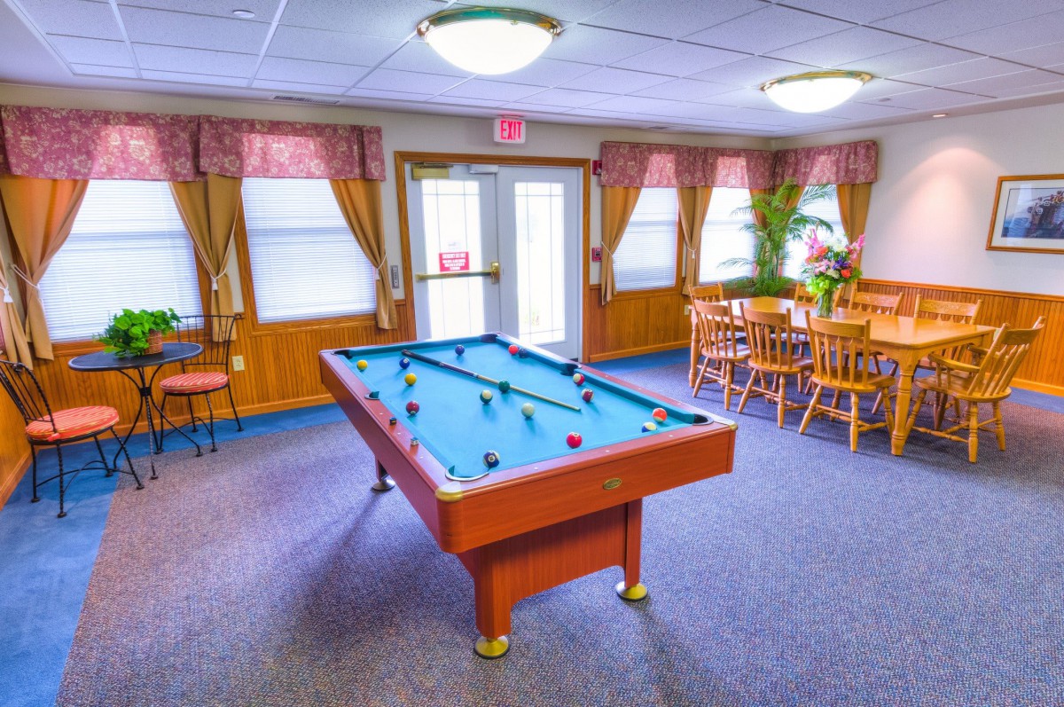 A cozy game room featuring a pool table and wooden furniture.
