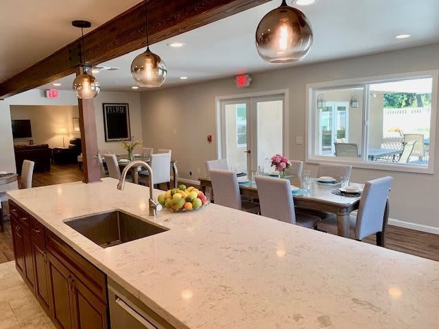A modern kitchen with a marble countertop, pendant lighting, and an open dining area.