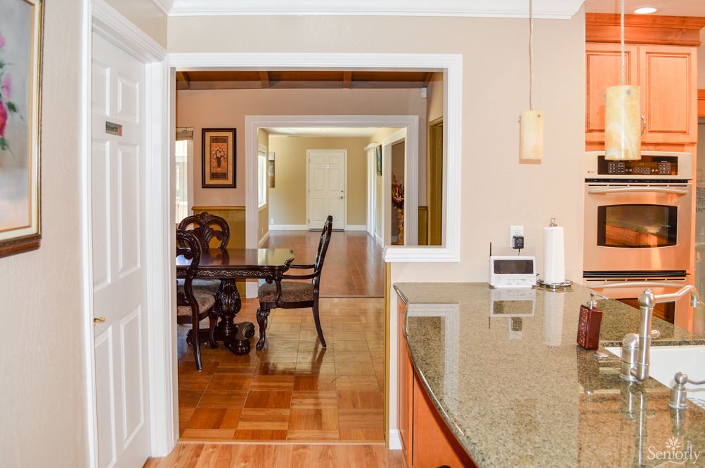 A view from the kitchen into a dining area with wooden flooring and a stylish table.