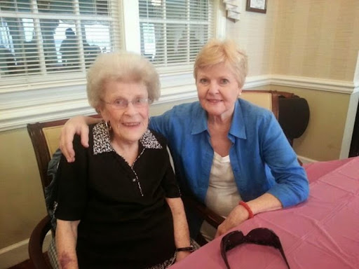 Two senior women enjoying a moment together, sharing smiles in a cozy indoor setting.