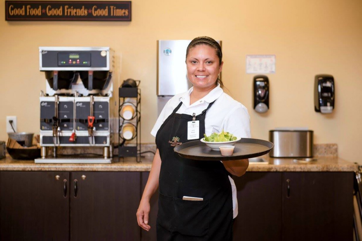A waitress in uniform holding a tray with food at a restaurant.