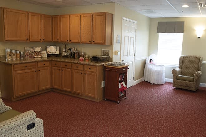A cozy kitchen corner with wooden cabinets and a carpeted floor.