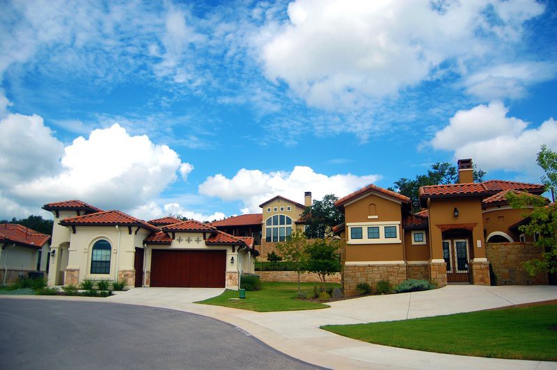 A suburban neighborhood with modern homes under a blue sky with clouds.