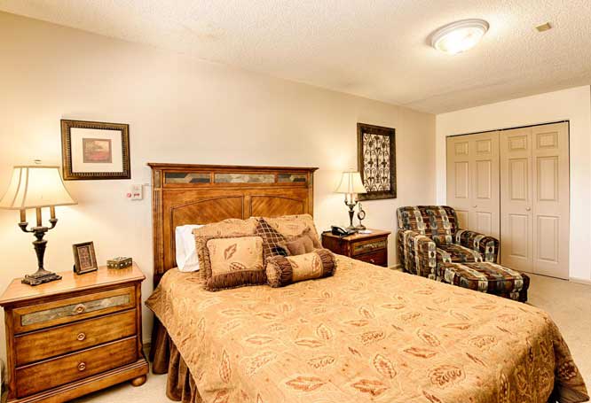 A cozy bedroom featuring a wooden bed frame, matching nightstands, and a comfortable armchair.