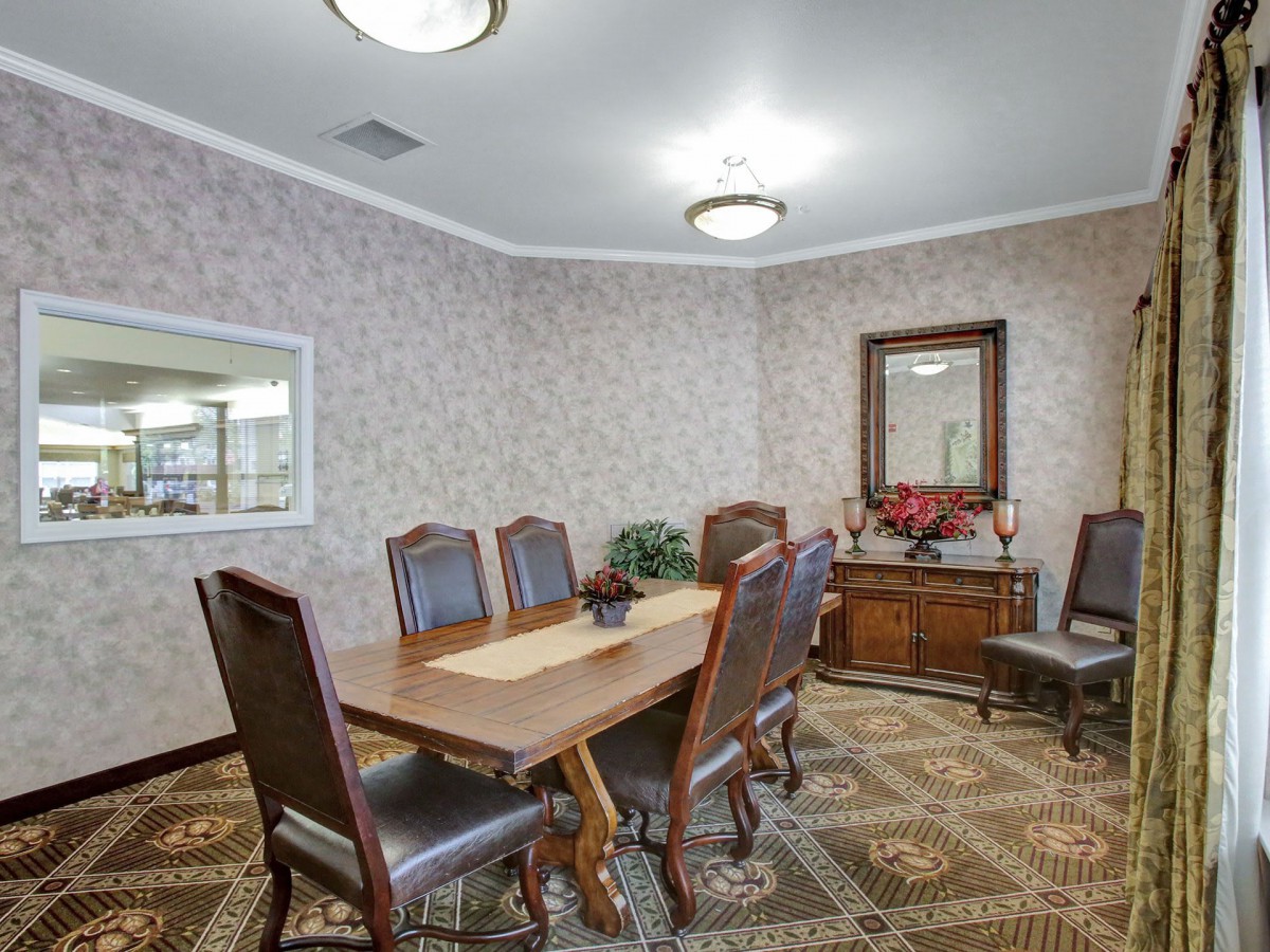 A formal dining room with elegant furniture, including a wooden table and upholstered chairs, adorned with a mirror and decorative items.