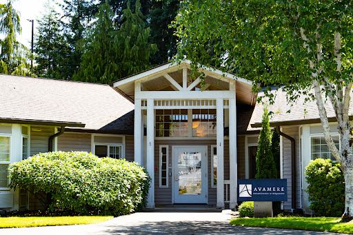 A welcoming entrance to a modern building surrounded by lush greenery.