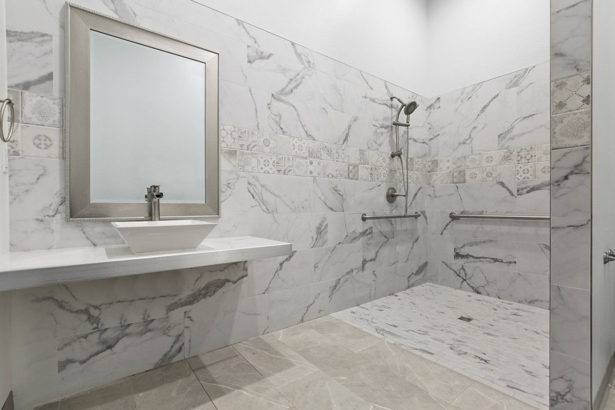 A modern bathroom with marble tiles and a walk-in shower.
