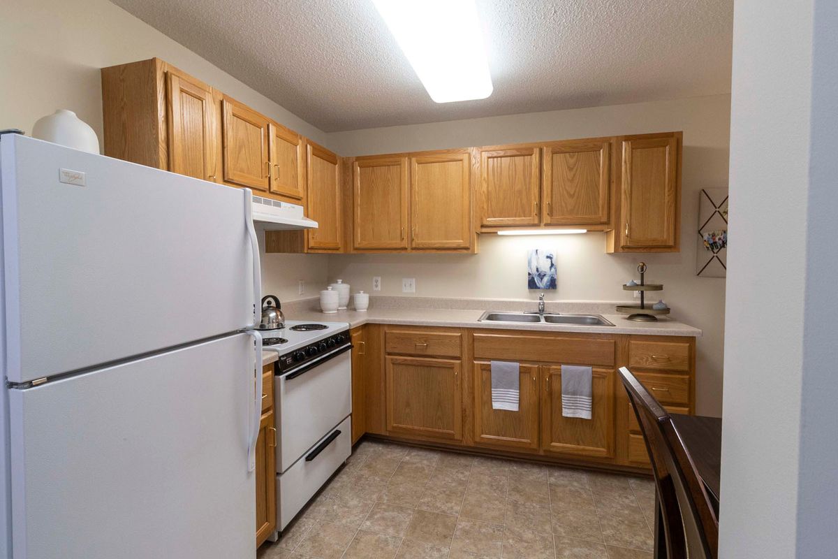 A kitchen with wooden cabinets, a refrigerator, and an oven.