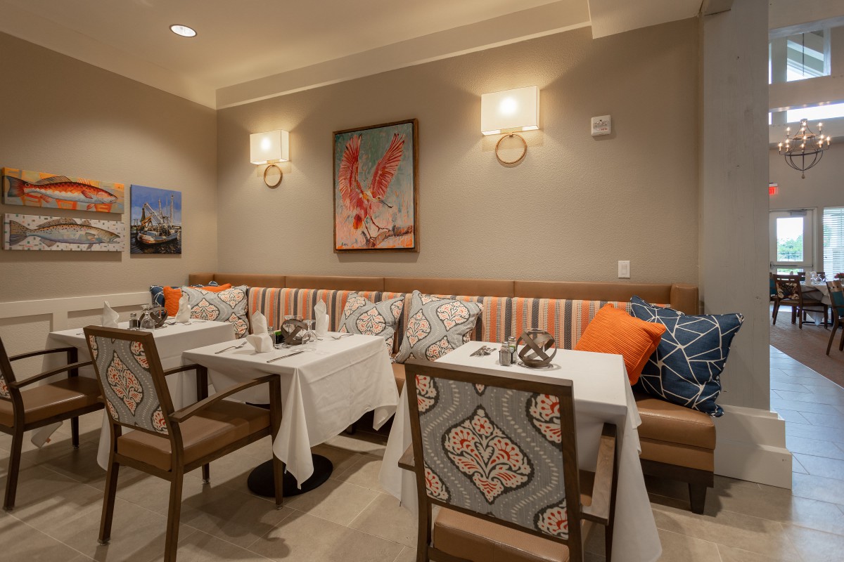 Cozy restaurant interior with elegantly set tables and decorative artwork on the walls.