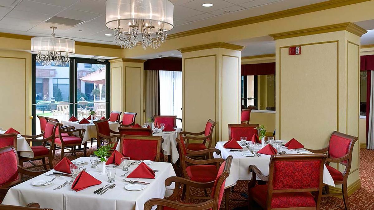 An elegant restaurant interior with red chairs and neatly set tables.