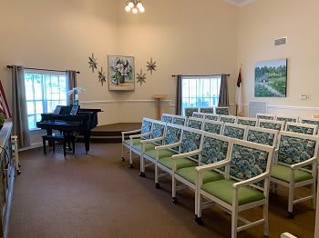 A well-lit room with arranged chairs, a grand piano, and decorative elements.