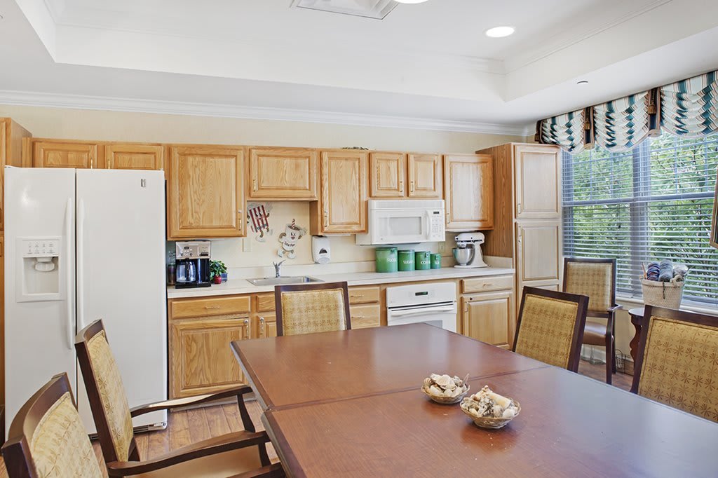 A modern kitchen with wooden cabinets and a dining area featuring a table and chairs.