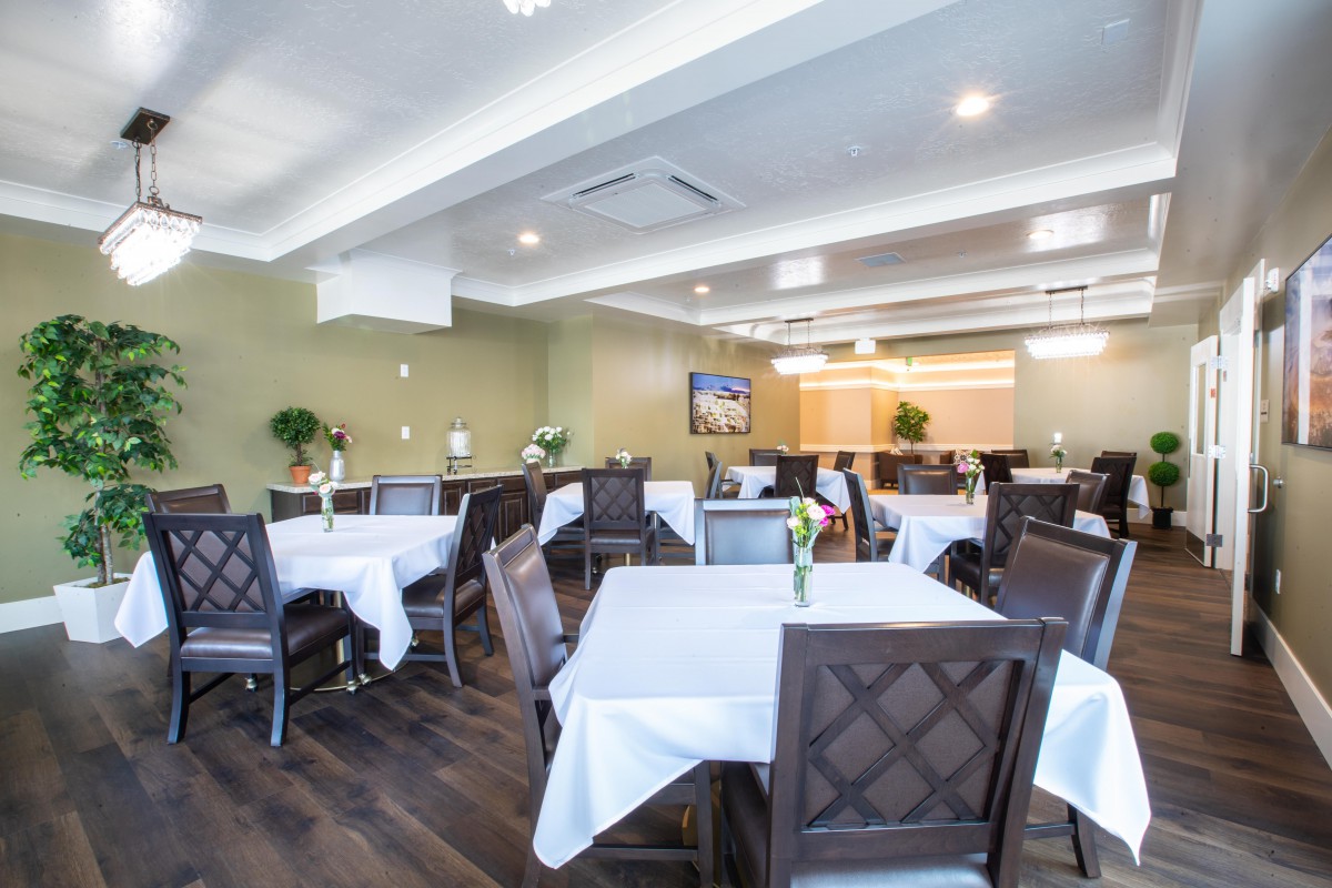 A modern dining room with neatly arranged tables and chairs, featuring elegant table settings.