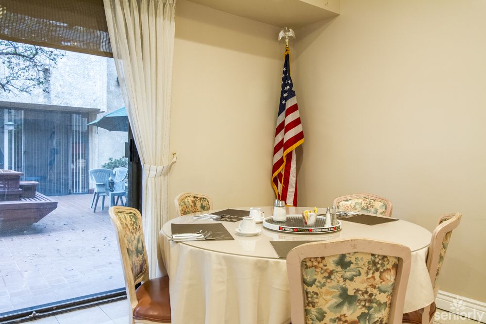 A cozy dining area with a round table and floral chairs, featuring an American flag in the corner.