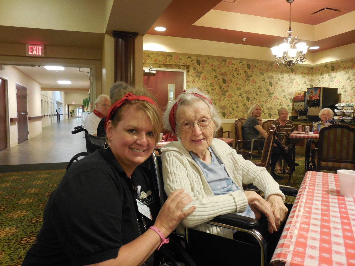 A caregiver and an elderly woman smiling together in a care home setting.