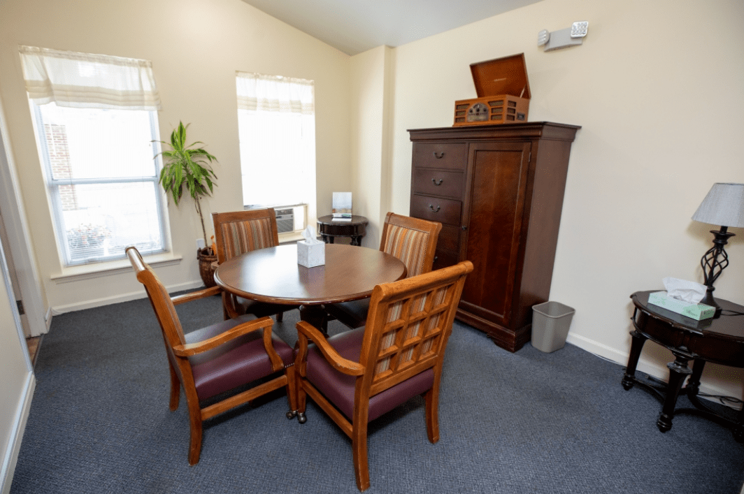 A small office meeting room with a round table and wooden chairs.