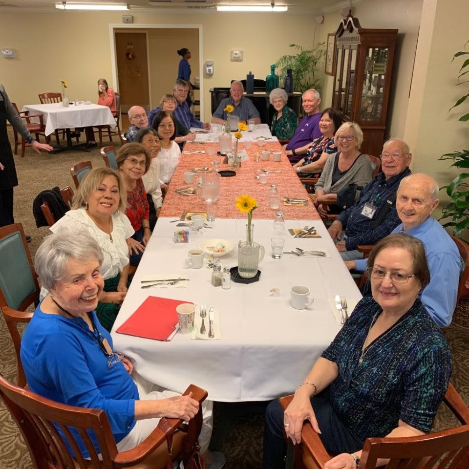 A group of people enjoying a meal together at a long dining table.