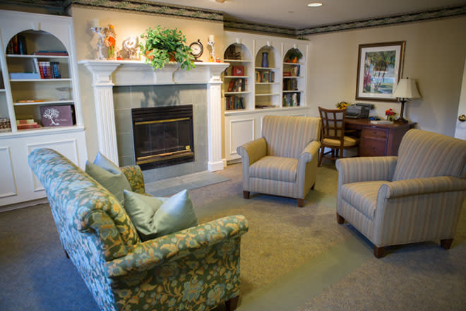 A cozy living room with a fireplace, comfortable seating, and decorative bookshelves.