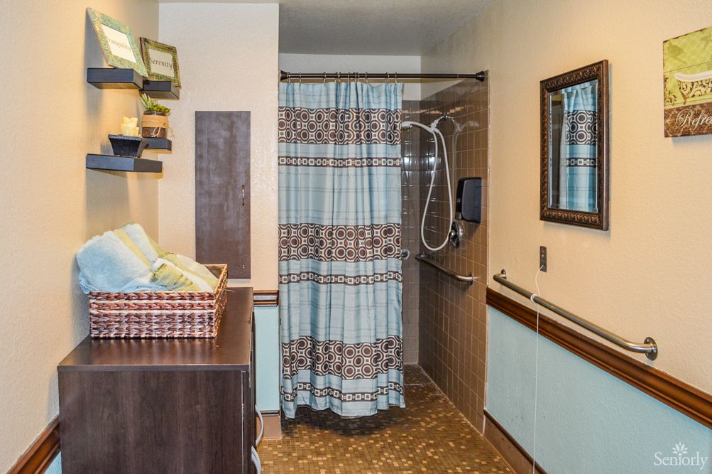 A well-organized bathroom with a shower area, featuring a striped curtain, shelves with towels, and a mirror.
