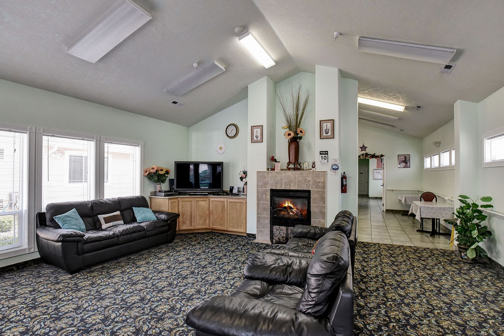 A cozy living room featuring leather sofas, a fireplace, and a TV setup.