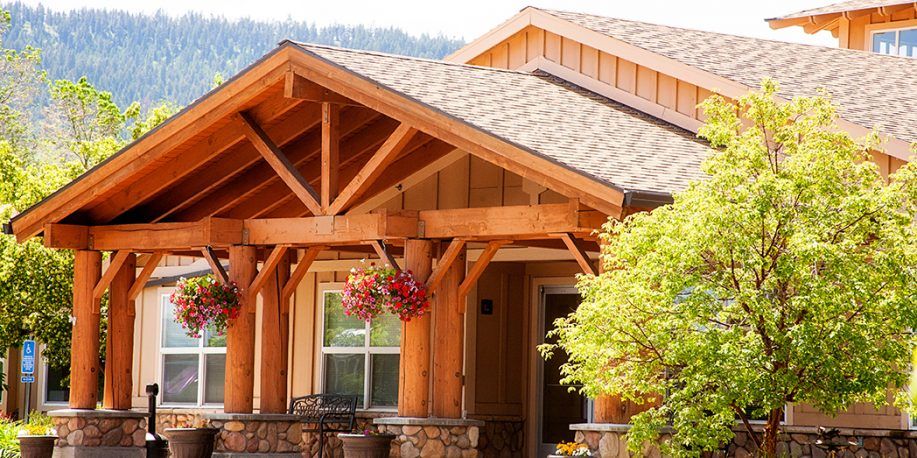 A charming wooden house with a welcoming porch adorned with hanging flowers.