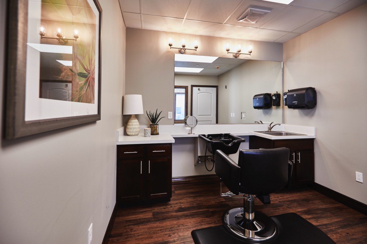 A modern hair salon with a stylish chair, sink, and large mirror.