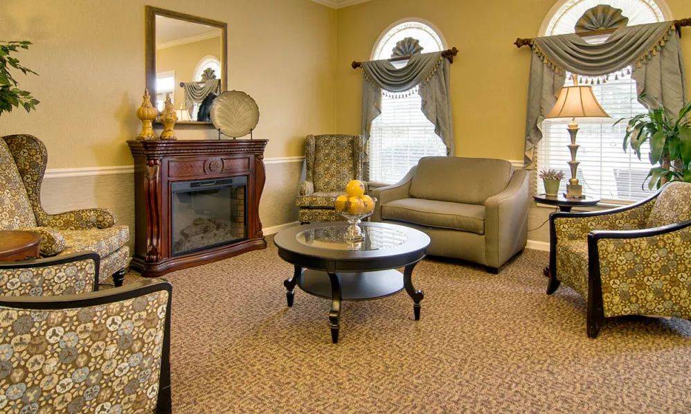 A cozy living room with classic decor featuring a sofa, armchair, and a fireplace.