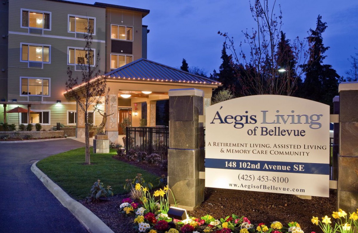 Aegis Living of Bellevue building illuminated at night with well-maintained landscaping and visible signage.