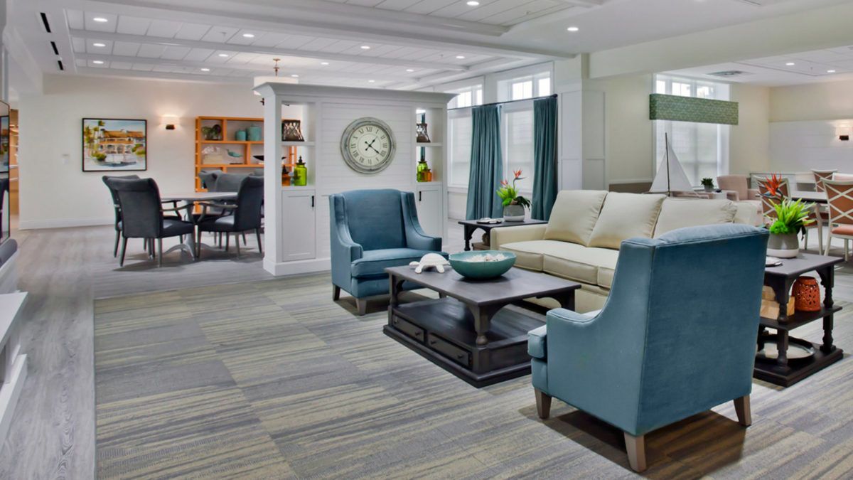 A modern living room with blue chairs, a cream sofa, and a dark coffee table, featuring elegant decor.
