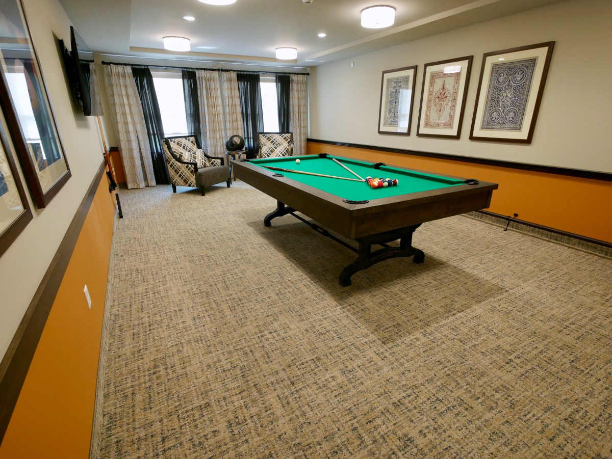 A cozy billiard room featuring a pool table and comfortable seating.