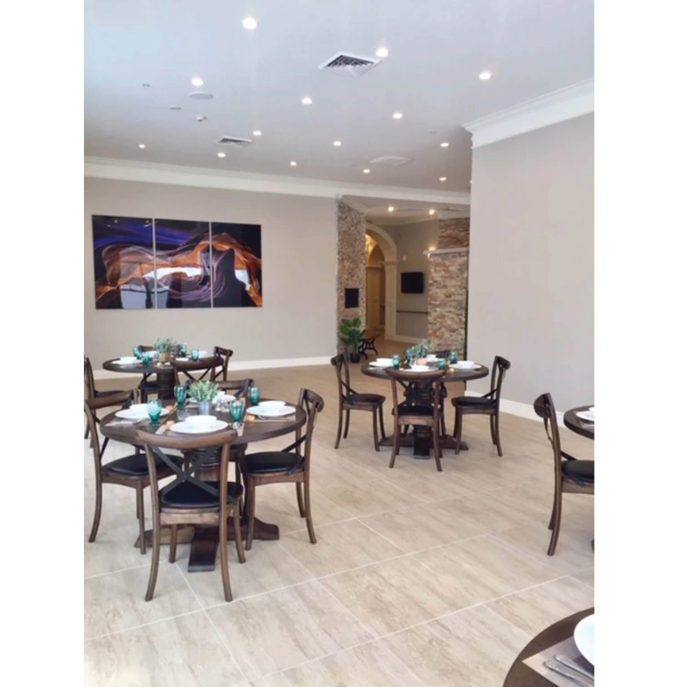 A modern restaurant interior with neatly arranged dining tables and chairs, featuring warm lighting and elegant decor.