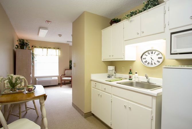 Bright kitchen area with white cabinets and a clock on the wall.