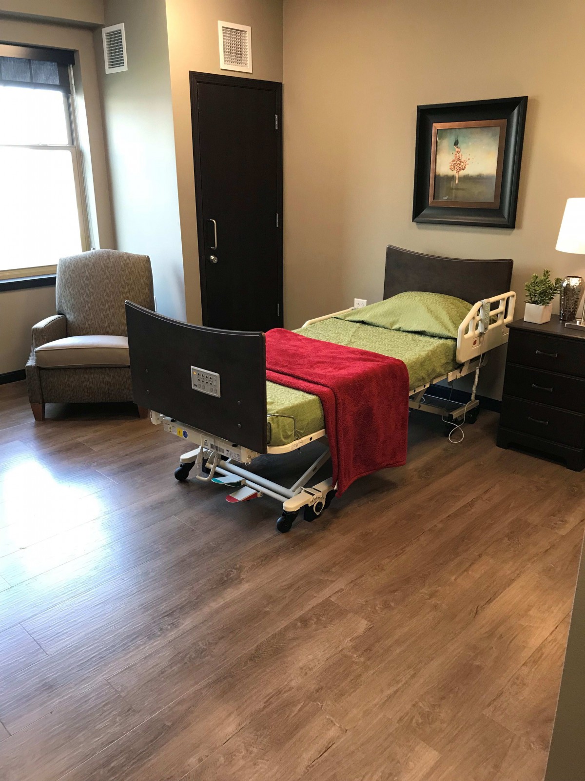 A hospital room with a bed and comfortable seating arrangement.