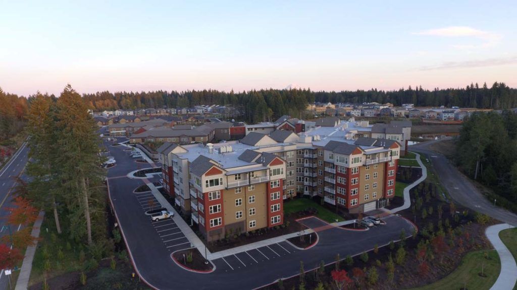 Aerial view of a suburban apartment complex with parking facilities and surrounding residential areas.