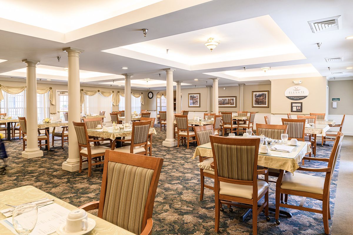 An empty, well-lit dining room with neatly arranged tables and chairs.