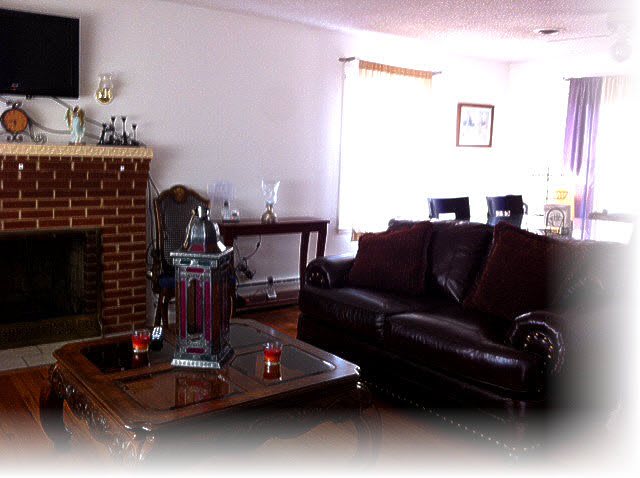 A cozy living room with a dark leather sofa, wooden table, and a brick fireplace.
