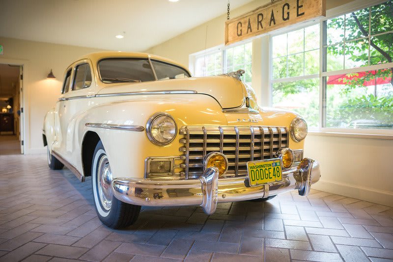 A vintage yellow classic car parked in a well-lit garage.