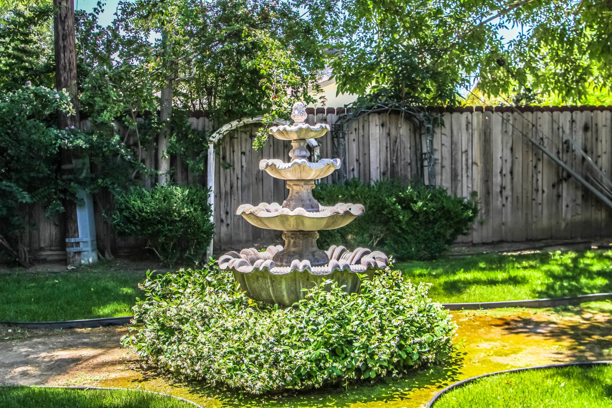 A beautiful multi-tiered fountain surrounded by lush greenery in a garden setting.
