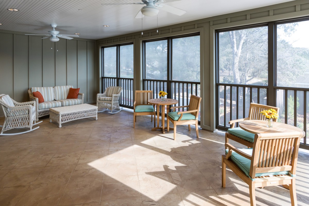 A bright sunroom furnished with comfortable seating and large windows.