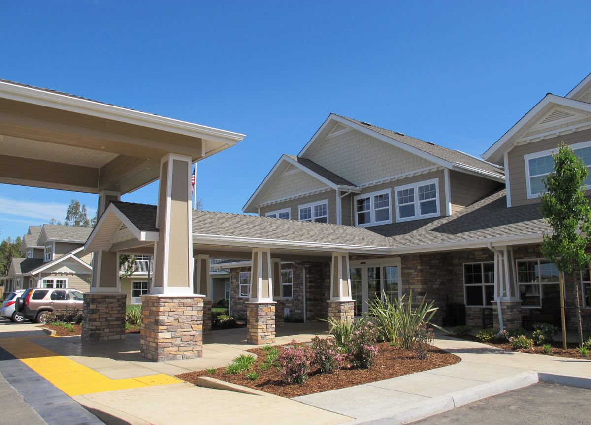 A modern residential building with landscaped surroundings under a clear blue sky.