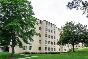 A multi-story residential building surrounded by trees and greenery.
