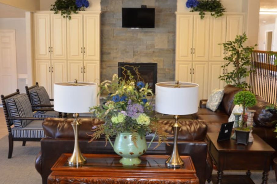 A beautifully decorated living room featuring a central table with ornate flowers and elegant lamps.